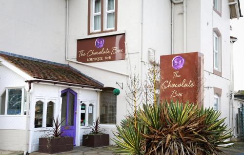 a white building with purple doors and signs on it at The Chocolate Box Hotel in Bournemouth