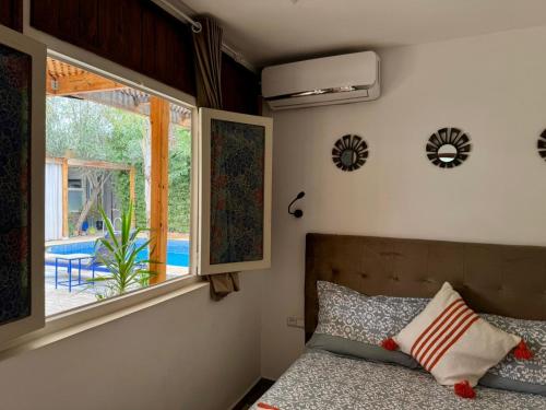 a bedroom with a bed and a window and a pool at Riad Eglantine in Touggana