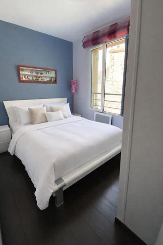 a large white bed in a blue room with a window at Belle Brise - Cozy apartment in city center in Cancale