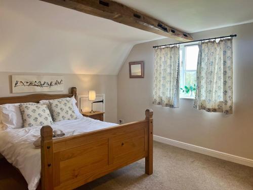 a bedroom with a wooden bed and a window at Locks Lane Cottage in Geldeston