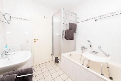 a white bathroom with a tub and a sink at Ferienwohnung am Moselufer in Cochem