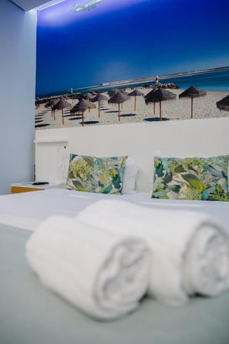 a white bed with umbrellas on the beach at Golden Beach Guest House & Rooftop Bar in Faro