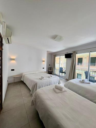 a room with three beds and a large window at Pensió Anna in Tossa de Mar