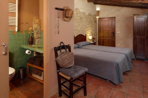 a bedroom with a bed and a chair and a bathroom at Can Marisch Les Arcades in Ventalló