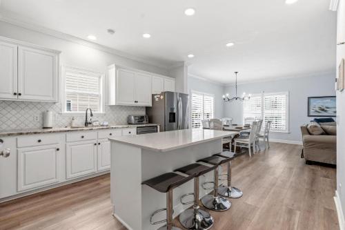 a kitchen with white cabinets and a kitchen island with bar stools at Antigua Breeze - 3rd Row - Windy Hill Section in Myrtle Beach