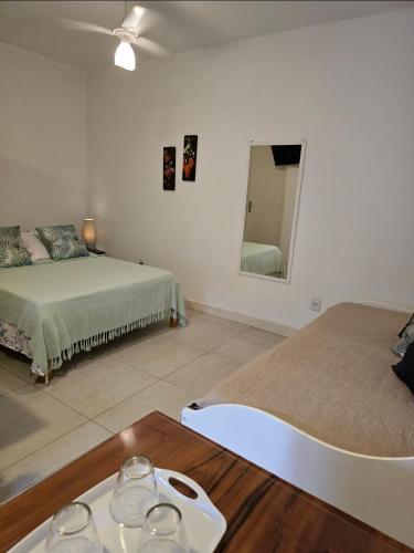 a room with two beds and a table and a mirror at Suites Nativa in Ubatuba