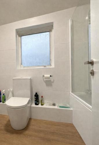 a bathroom with a toilet and a shower and a window at Shooters Hill Stay in London