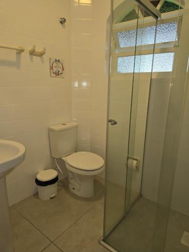 a bathroom with a toilet and a glass shower at Suites Nativa in Ubatuba