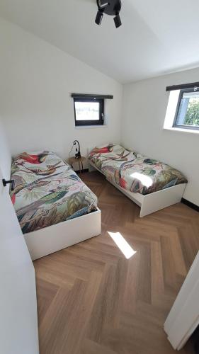 two beds in a room with a wooden floor at De Platwever 3C in Zelhem