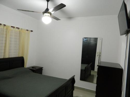 a bedroom with a bed and a ceiling fan and a mirror at Residencial Vista Del Bosque in Santiago de los Caballeros