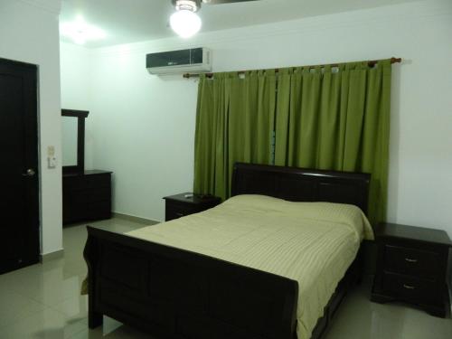 a bedroom with a bed and a green curtain at Residencial Vista Del Bosque in Santiago de los Caballeros