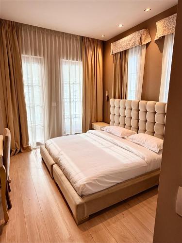 a large bed in a room with windows at Hotel Rezidenca Desaret in Berat