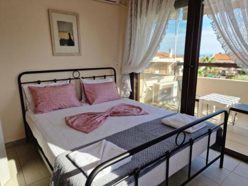 a bedroom with a bed with pink pillows and a balcony at Lela's House in Yerakiní