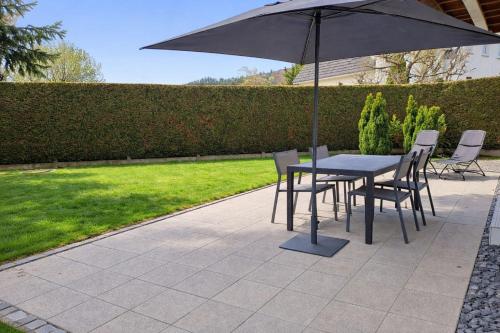 a table and chairs with an umbrella on a patio at La Ptite Maison Gîte Alsace à la campagne in Sickert