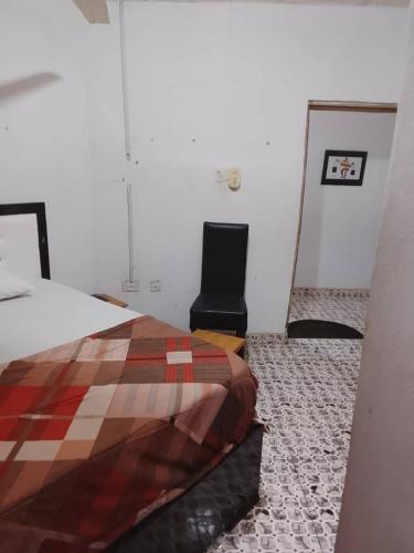 a bedroom with a bed and a black chair at July 16th hotel and event centre in Alagbado
