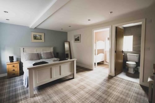 a bedroom with a bed and a bathroom with a toilet at Barneys cottage with hot tub in the Lake District National Park in Lake District National Park