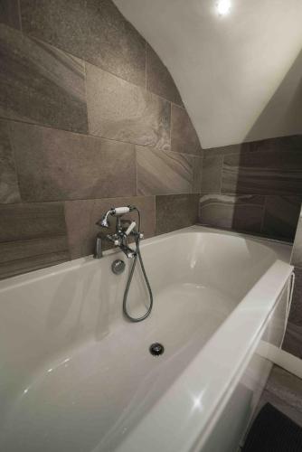 a white bath tub with a faucet in a bathroom at Barneys cottage with hot tub in the Lake District National Park in Lake District National Park