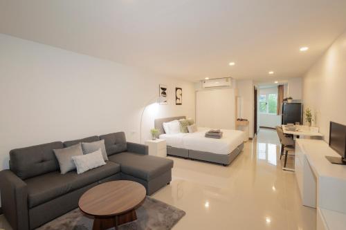 a living room with a couch and a bed at Elegant Modern White Suite in Chiang Mai