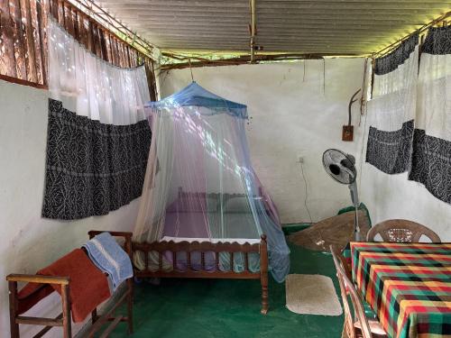 a room with a bed and a table and curtains at Jungle Room in Talalla South