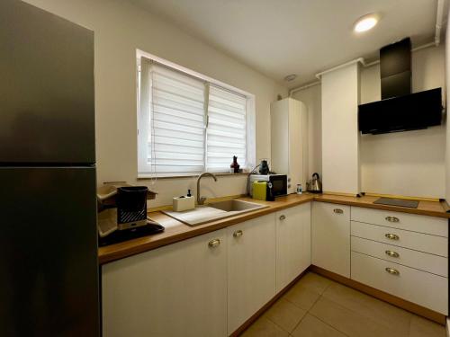 a kitchen with white cabinets and a sink and a window at Nori Studio #Garden&Pool in Ştefăneştii de Sus