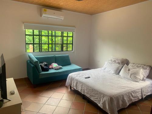 a bedroom with a bed and a couch and a window at Cabaña AWA in Puerto Salgar