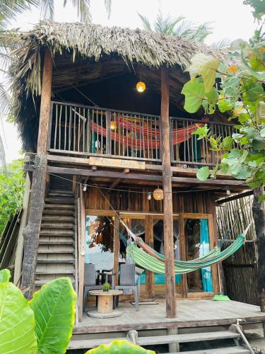 a house with a hammock in front of it at HOSTAL Estrellas del tayrona playa mendihuaca in Santa Marta