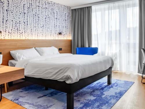 a bedroom with a bed and a blue chair at ibis Styles Relax Roznov pod Radhostem in Rožnov pod Radhoštěm