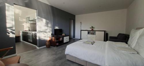 a bedroom with a white bed and a kitchen at Stylish 1-bedroom apartment for 3 with balcony, free parking & river views in a quiet area in Prievidza