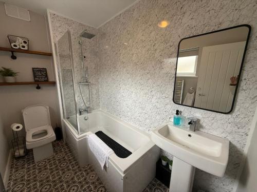a bathroom with a tub and a sink and a mirror at Homely house, foot of Snowdonia with private parking in Llanberis