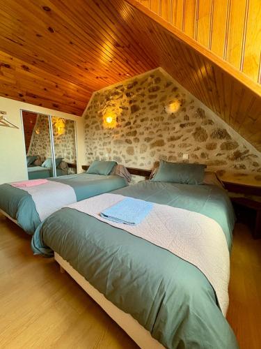 a bedroom with two beds and a stone wall at Lo Soulenquo à Fonteilles sur le GR 65 in Golinhac