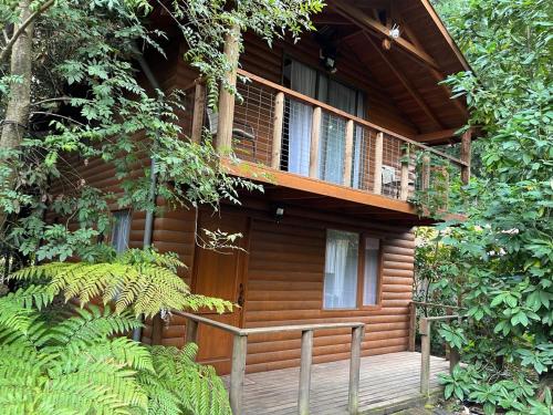 eine Holzhütte mit Balkon im Wald in der Unterkunft cabañas arca in Pucón