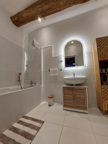 a bathroom with a sink and a tub and a mirror at Moulin de Monpoisson in Le Puy