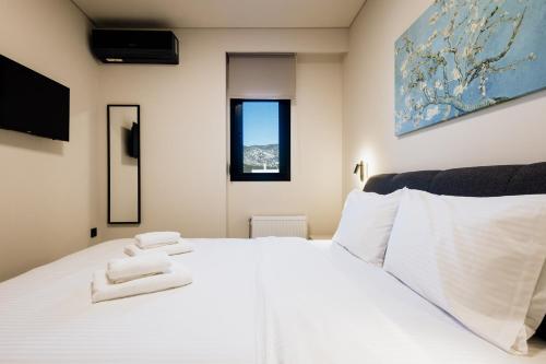 a bedroom with a white bed with towels on it at Dreamer's Luxury Suites in Volos