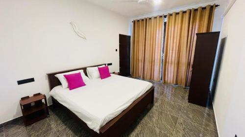 a bedroom with a bed with two pink pillows at Seaside Residence Negombo in Negombo