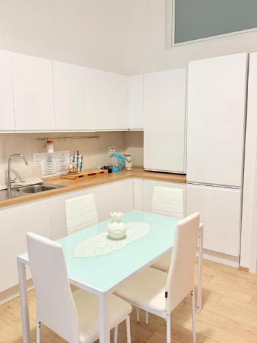 a white kitchen with a blue table and white chairs at Dimora Vanni "civico 5" "civico 9" in Polignano a Mare