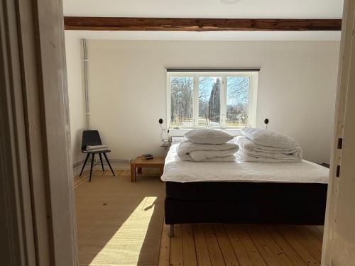a bedroom with a bed with white sheets and a window at Fiskarhuset seaside cottage 2-6 pax in Sjöbo