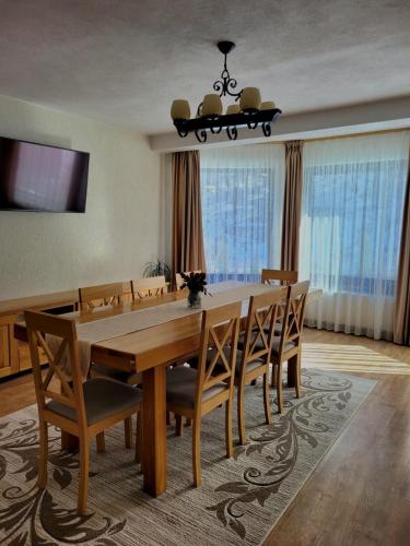 a dining room with a wooden table and chairs at Cabana Valea Muntelui in Poiana Mărului