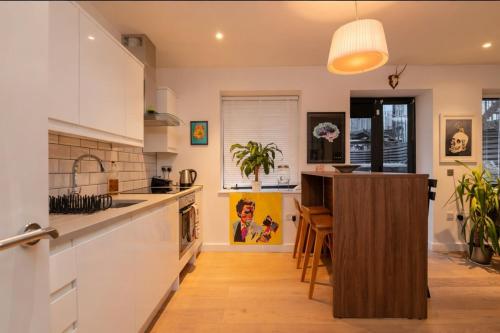 a kitchen with white cabinets and a wooden island at cozy 1 bedroom flat in Soho in London