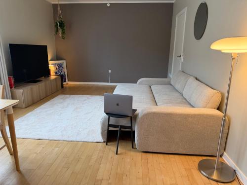 a living room with a couch and a laptop on a stool at Charming studio apartment in the heart of Nørrebro, Copenhagen in Copenhagen