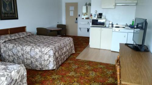 a hotel room with a bed and a kitchen at Travel Inn Hearst in Hearst