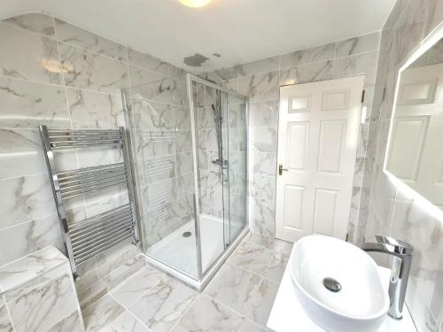 a white bathroom with a shower and a sink at Leabrook House in Castlemaine