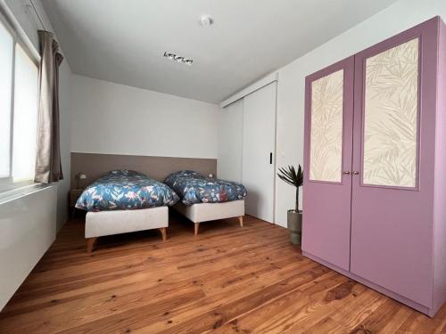 ein Schlafzimmer mit zwei Betten und einer lila Tür in der Unterkunft De Durme in Temse