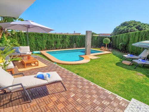 a backyard with a swimming pool with chairs and an umbrella at Villa Serena in Mijas Costa