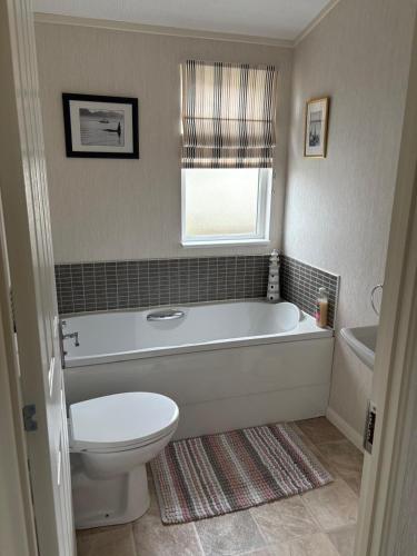 a bathroom with a tub and a toilet and a window at par 3 in Wisbech