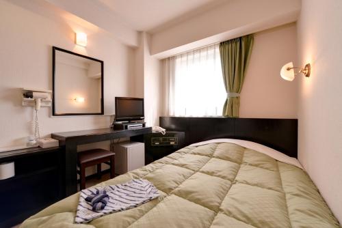 a hotel room with a bed and a desk and a window at Plaza Hotel Fujinoi in Hita