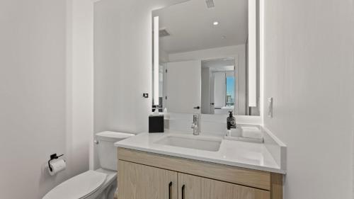 a white bathroom with a sink and a toilet at Sentral Forme Houston in Houston