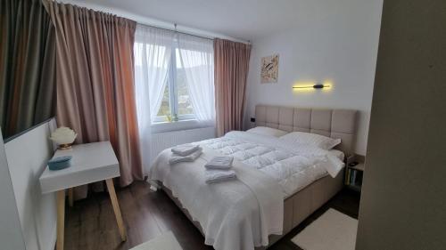 a bedroom with a white bed and a window at Solovan Hill in Sighetu Marmaţiei
