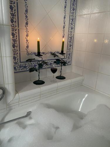 a bath tub with two candles and a mirror at Villa Rose in Seignosse