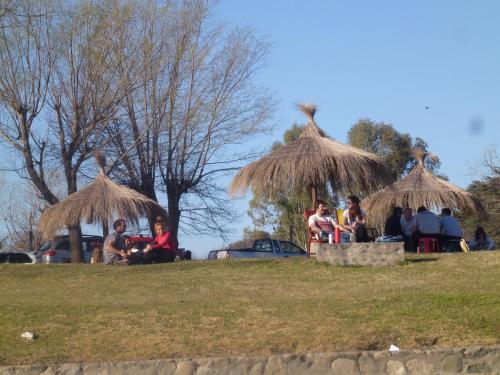 a group of people sitting under straw umbrellas at Complejo Leon in Villa Rumipal