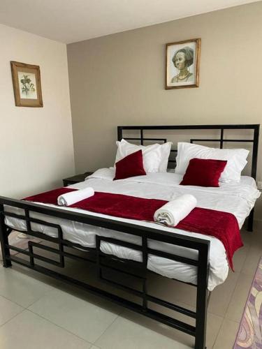 a large bed with red and white pillows on it at Katojo Quick Rides and stays in Arusha